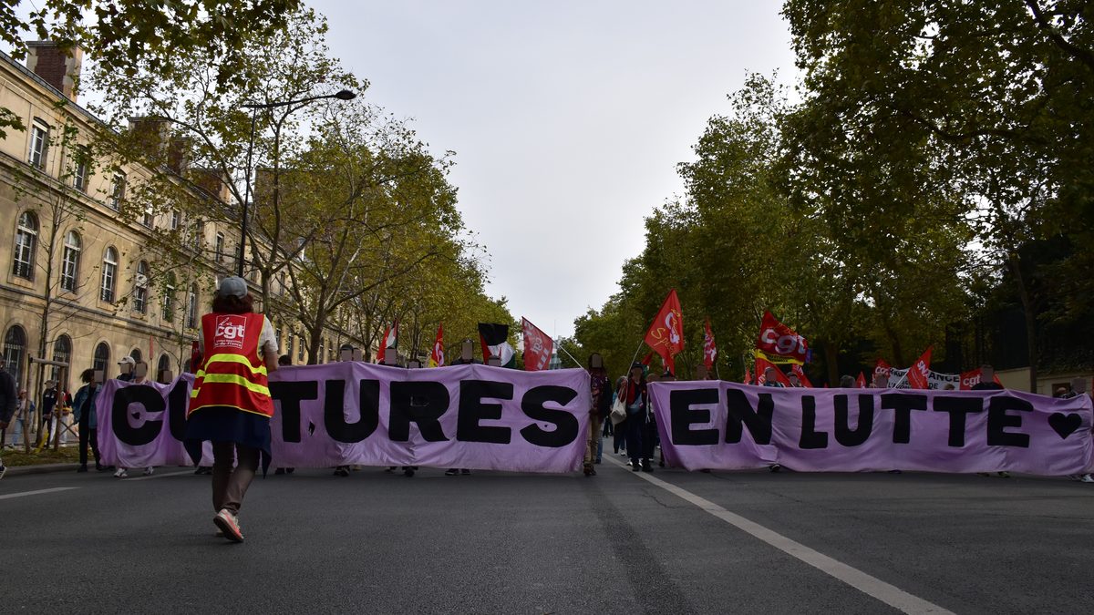 Tête de cortège derrière une banderole « Cultures en lutte » sur un boulevard parisien arboré, drapeaux de la CGT